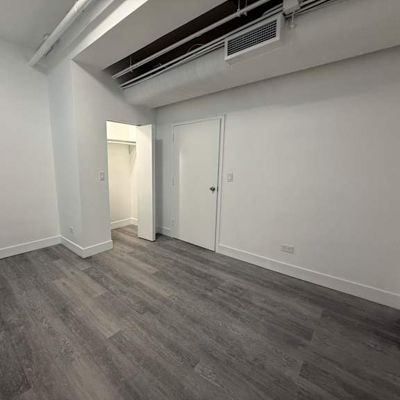 a room with grey flooring and white walls, featuring a door and a window.