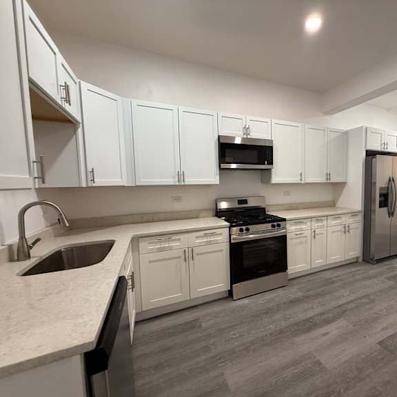 a kitchen with white cabinets and a grey floor.