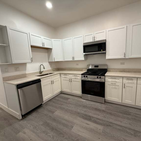 a kitchen with white cabinets and a grey floor.