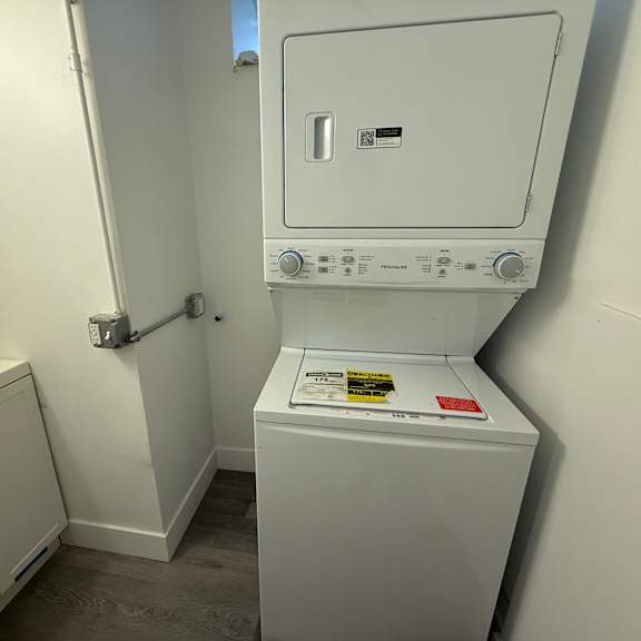 a white dryer is in a small room with a sink.