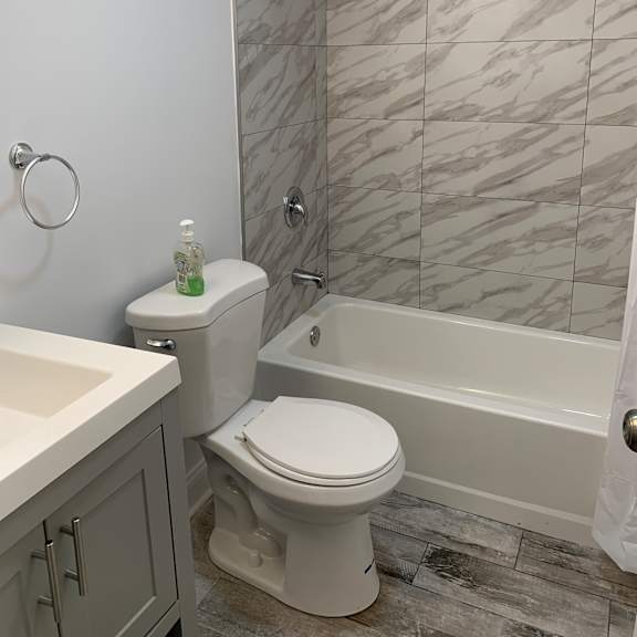 a white toilet in a bathroom with grey tiles.