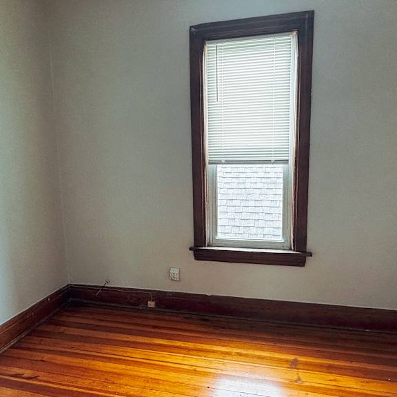 a room with a wooden floor and a window with blinds.