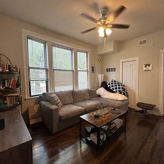 a living room with a couch, a coffee table, and a ceiling fan.