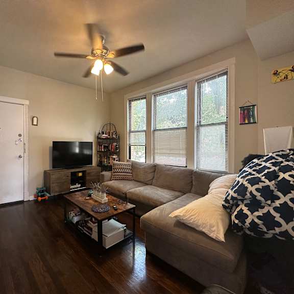 a living room with a couch, a television, and a ceiling fan.