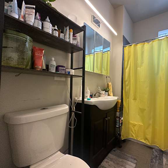 a bathroom with a yellow shower curtain and a white toilet.