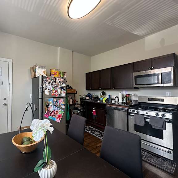 a kitchen with a black table and chairs and a fridge covered in magnets.