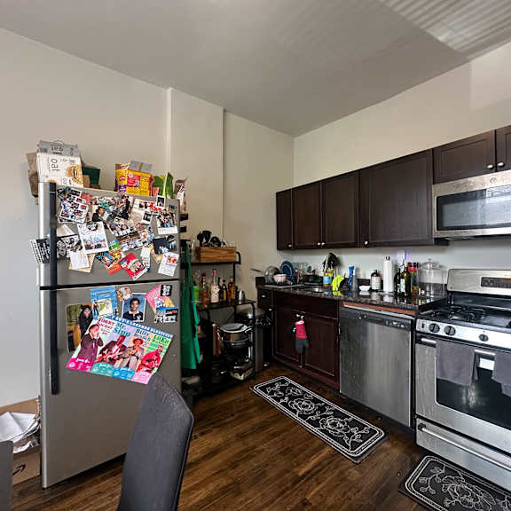 a kitchen with a refrigerator covered in flyers and a stove top oven.