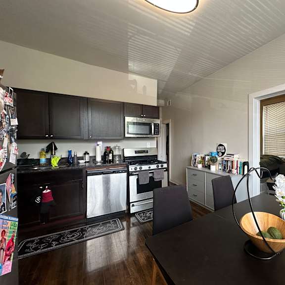a modern kitchen with dark wood floors and black countertops.