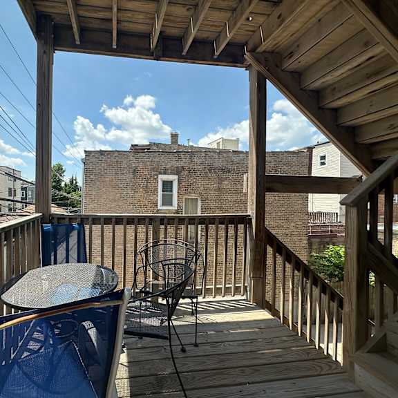 a wooden deck with a table and chairs overlooking a brick building.