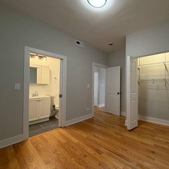 a room with a wooden floor and a white wall with a closet and a door.