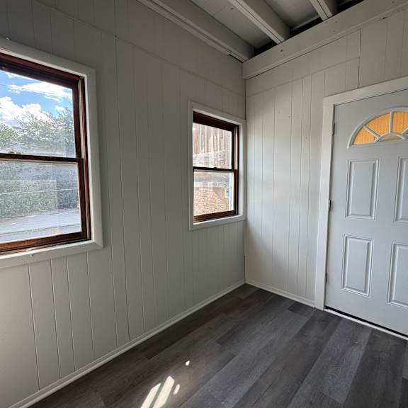 a room with a white door and two windows.