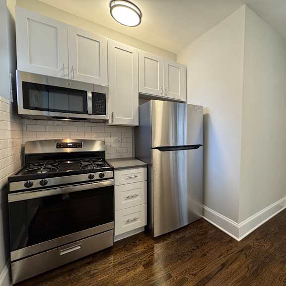 a kitchen with a stove, refrigerator, and cabinets.