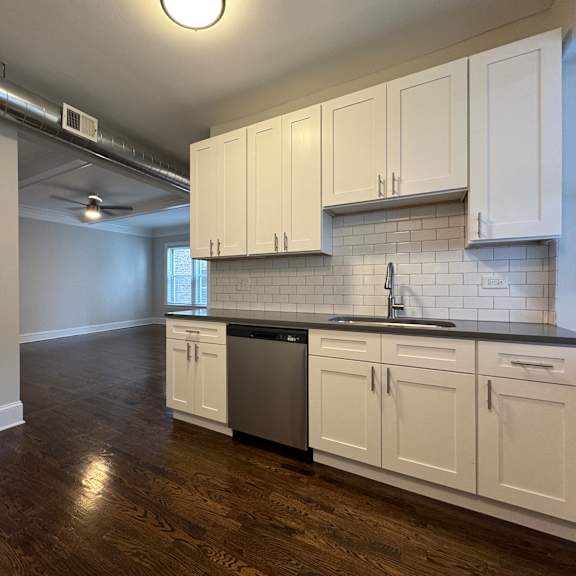 a kitchen with white cabinets and a black countertop.
