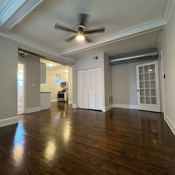 a room with a ceiling fan and wooden flooring.