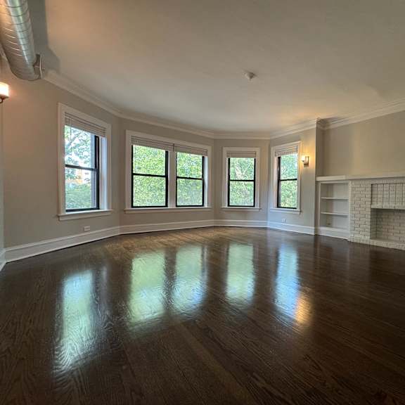 a large empty room with wooden floors and a fireplace.
