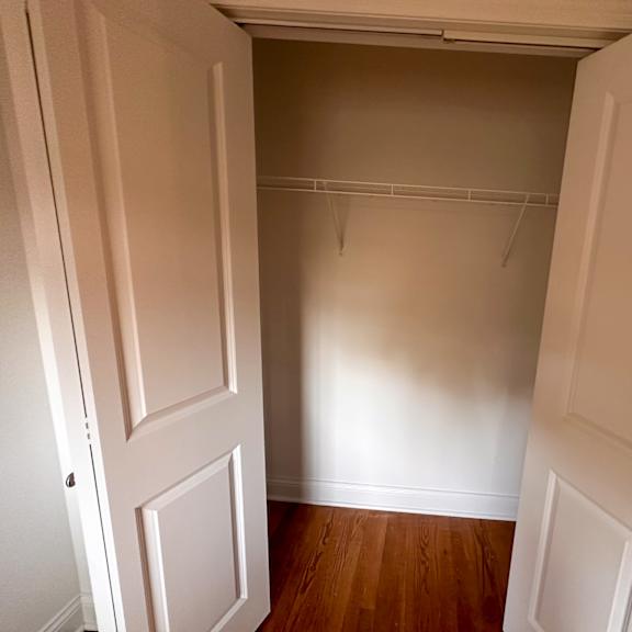 a white door is open to a room with a wooden floor.