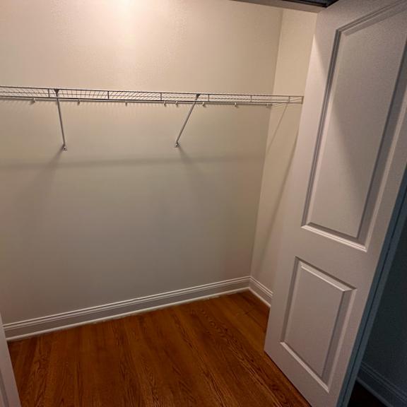 a white closet with a wooden floor and a white door.