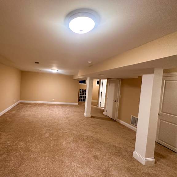 a spacious room with beige carpeting and white columns.