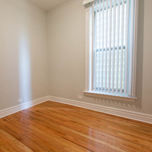 a room with wooden floors and a window with blinds.