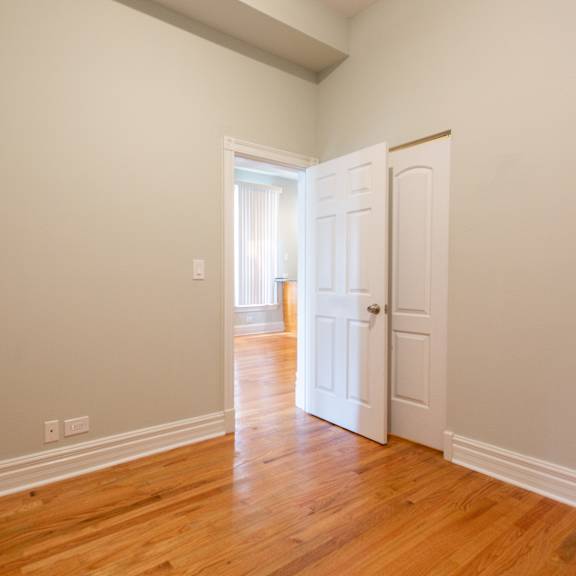 a room with a white door and wooden floor.