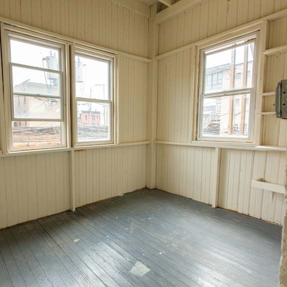 a room with wooden floors and two windows.