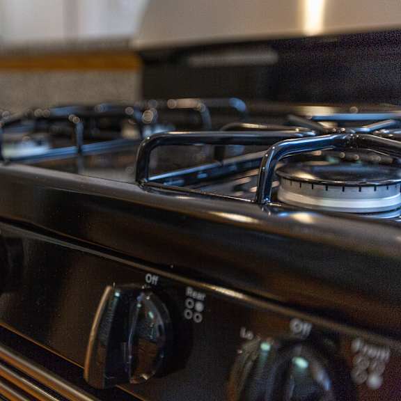 a close up of a black gas stove with four burners and knobs for controls.