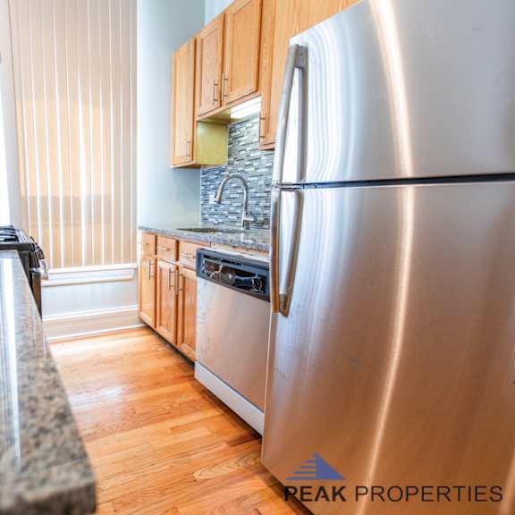 a kitchen with a granite countertop and a stainless steel refrigerator.