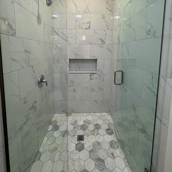 a bathroom with a marble tile floor and walls.