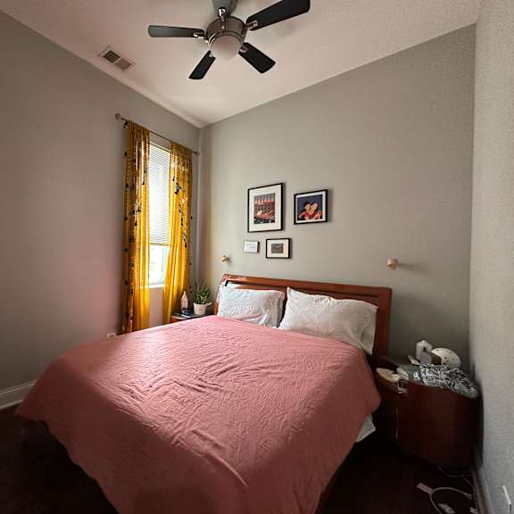 a bedroom with a bed, nightstand, and a ceiling fan.