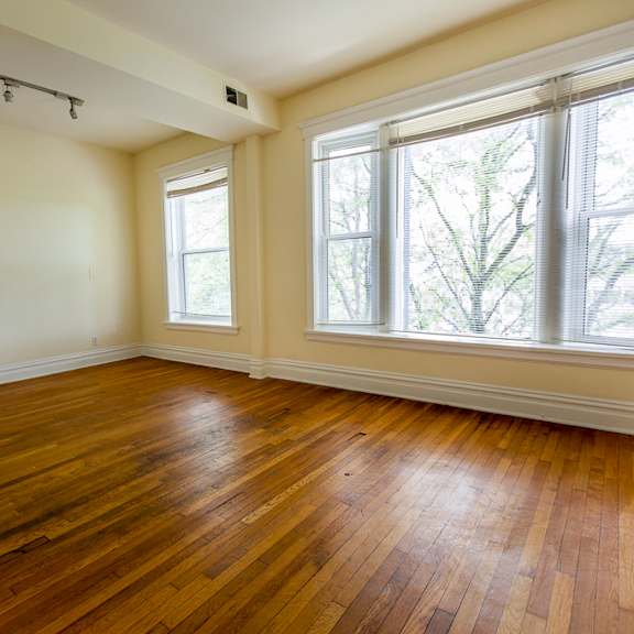 an empty living room with wood floors and large windows