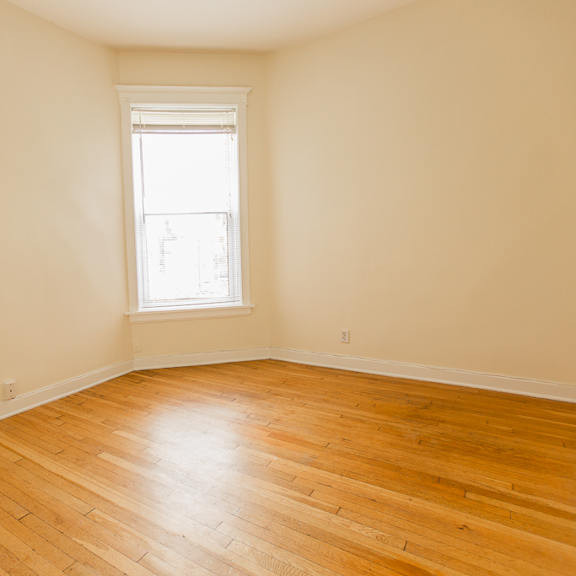 an empty room with wooden floors and a window