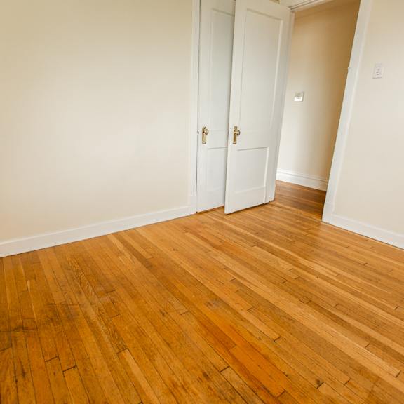 an empty living room with wood floors and white walls