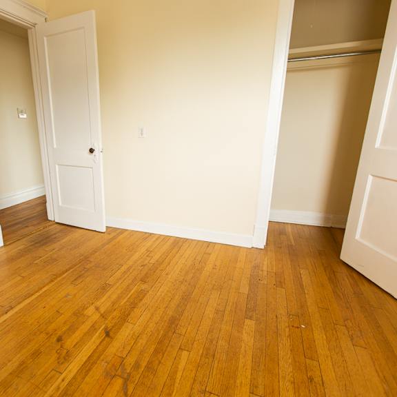 an empty living room with wood floors and a closet