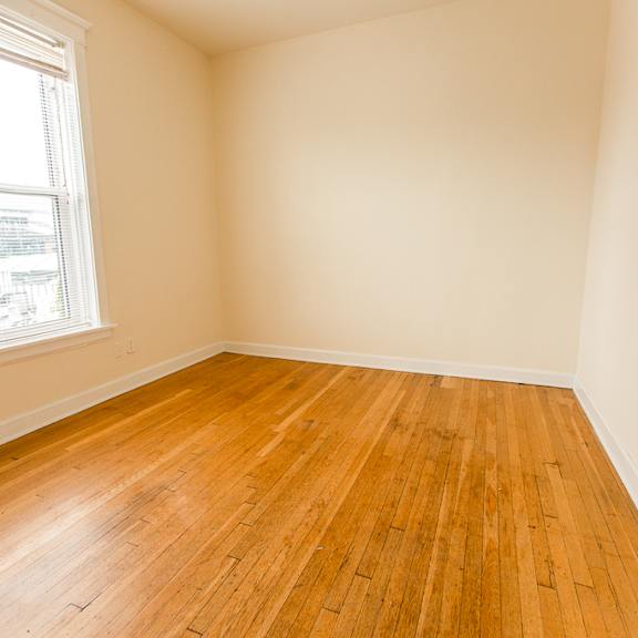 an empty room with wooden floors and a window