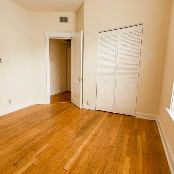 an empty living room with wood floors and a closet
