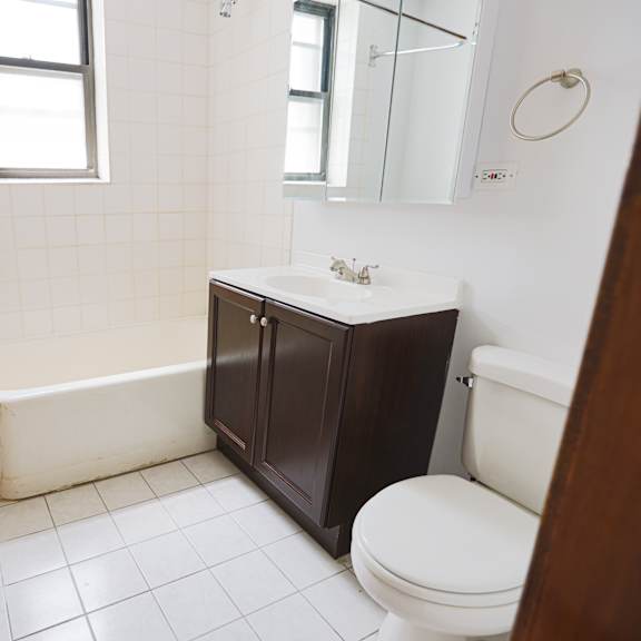 a white tiled bathroom with a wooden door.
