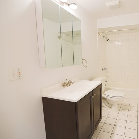 a white bathroom with a sink, toilet, and shower.