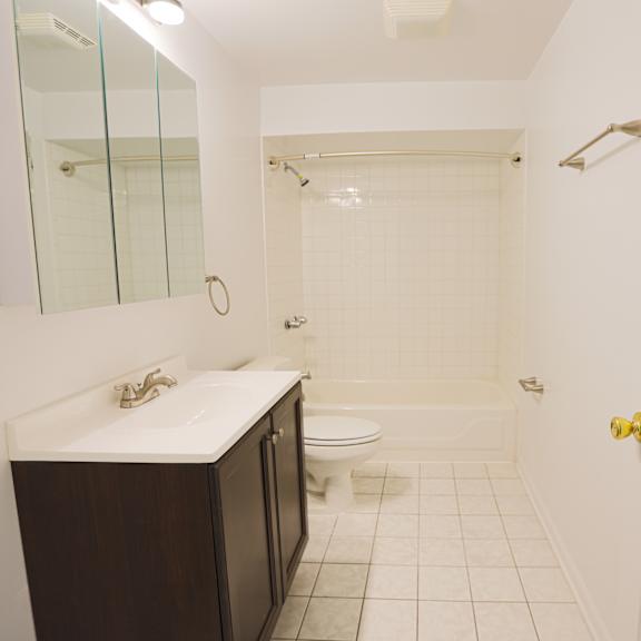 a white bathroom with a sink, toilet, and shower.