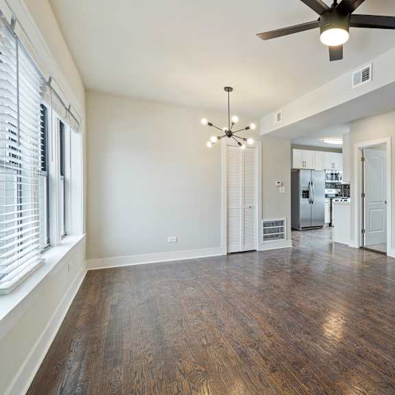 a spacious room with a ceiling fan and hardwood floors.