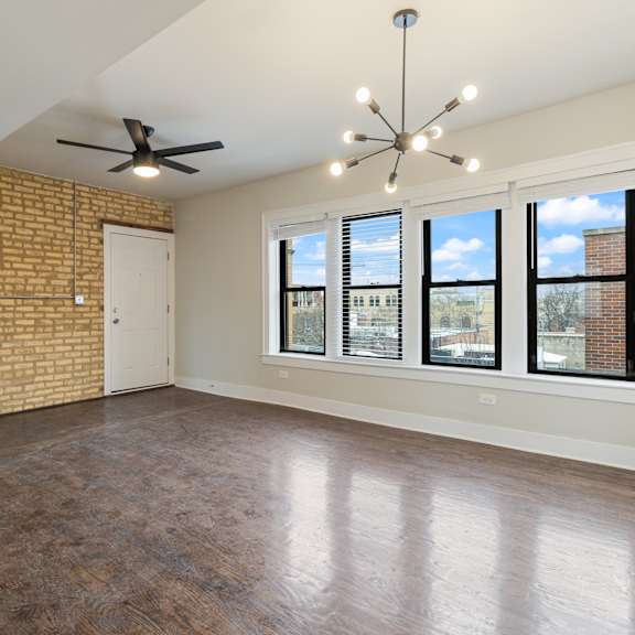 a room with a brick wall and a ceiling fan.