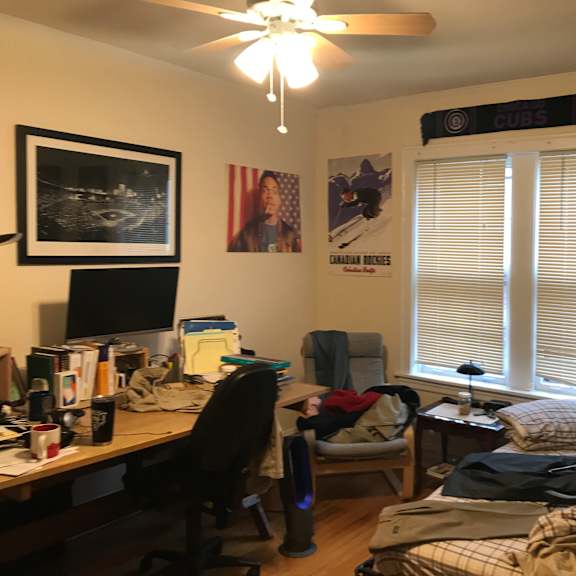 a bedroom with a desk and a bed and a window