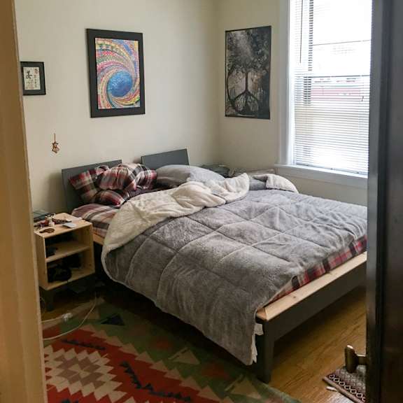a bedroom with a bed, a ceiling fan, and two pictures on the wall.