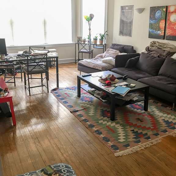 a living room with a brown couch and a rug.