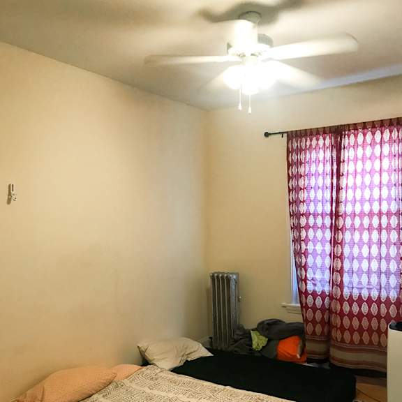 a bedroom with a bed, a ceiling fan, and a window with curtains.