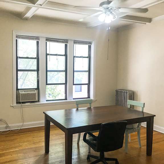 a room with a table and chairs and a window with an air conditioner.