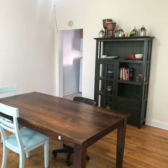 a wooden table with a blue chair in front of a black bookshelf.