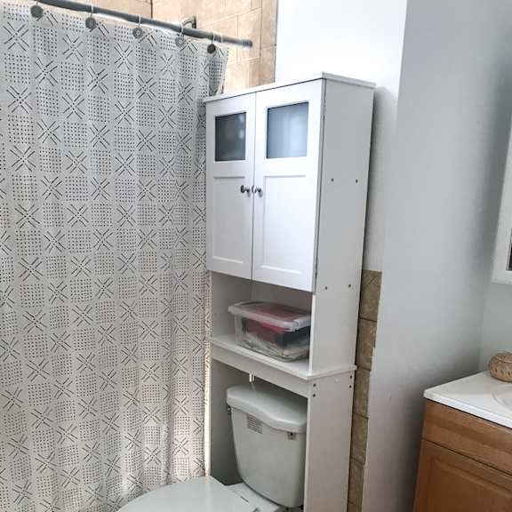 a white toilet with a white cabinet above it in a bathroom.