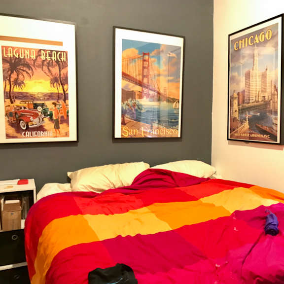 a bed with a colorful comforter and three pictures on the wall