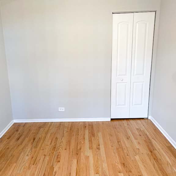 a room with a white door and wooden flooring.