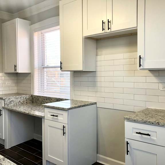 a kitchen with white cabinets and granite countertops.